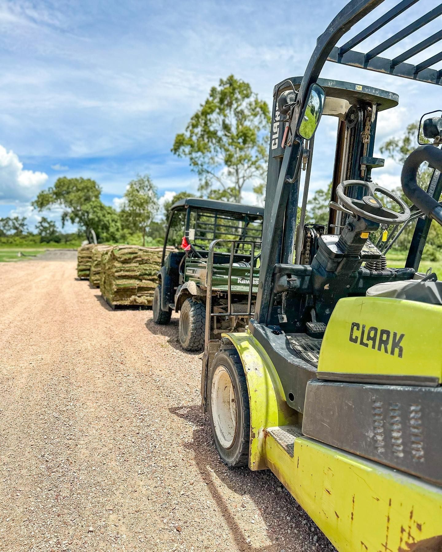Forklift Pulling Pallets of Materials with A Utility Vehicle on A Gravel Road, Sunny Day — Top Notch Turf in Rasmussen, QLD