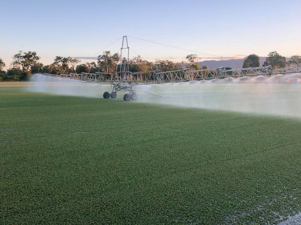 Irrigation System Watering a Green Field, Creating a Mist, with Mountains — Top Notch Turf in Rasmussen, QLD