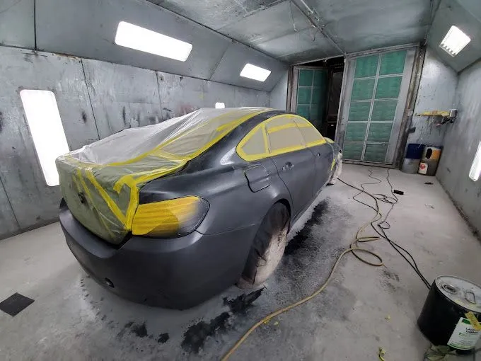 A car is being painted in a paint booth.
