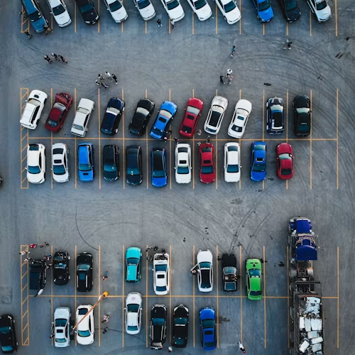 Overhead view of a parking lot with rows of parked cars in various colors