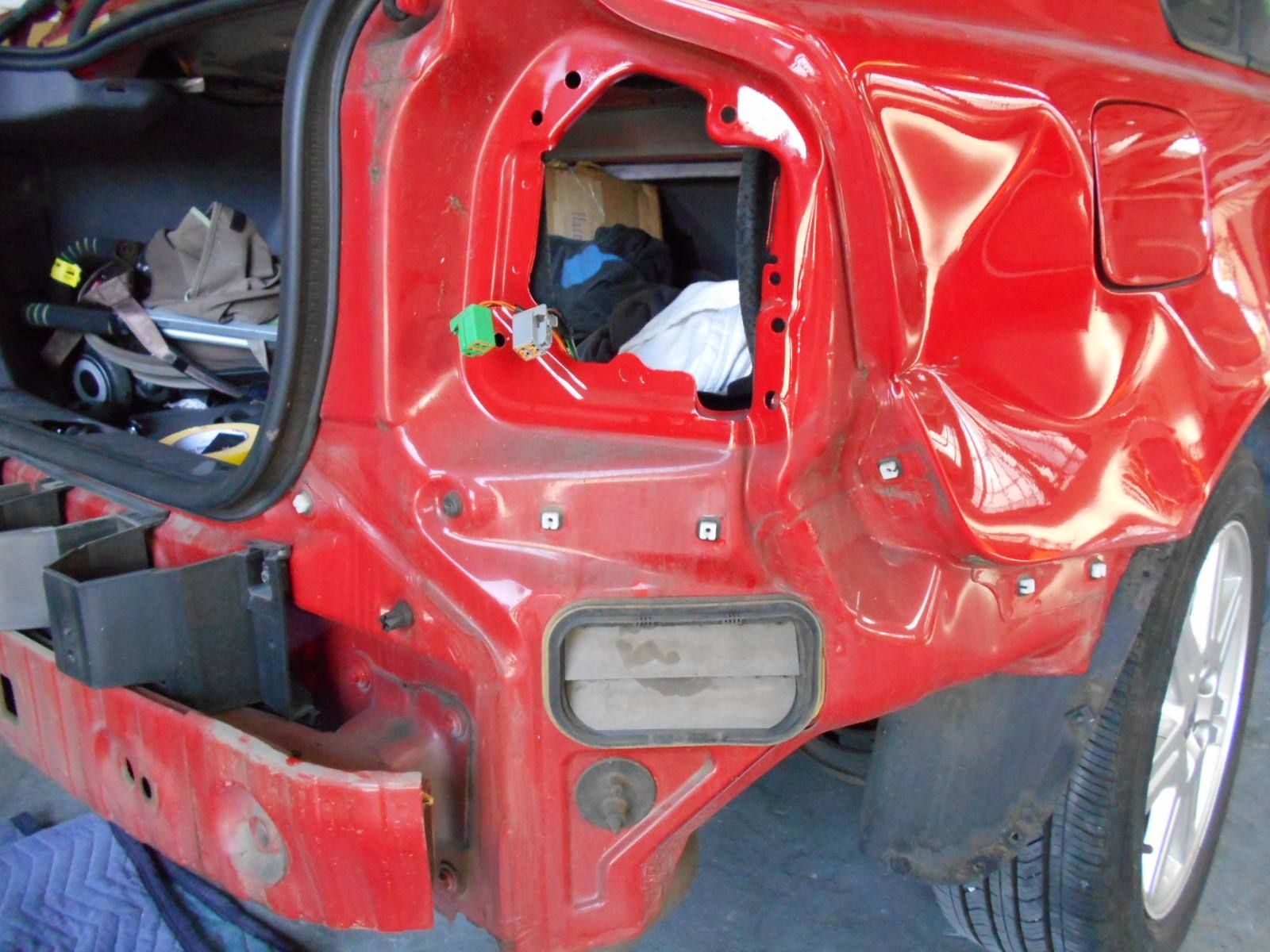 A red car that has been damaged is sitting on the ground