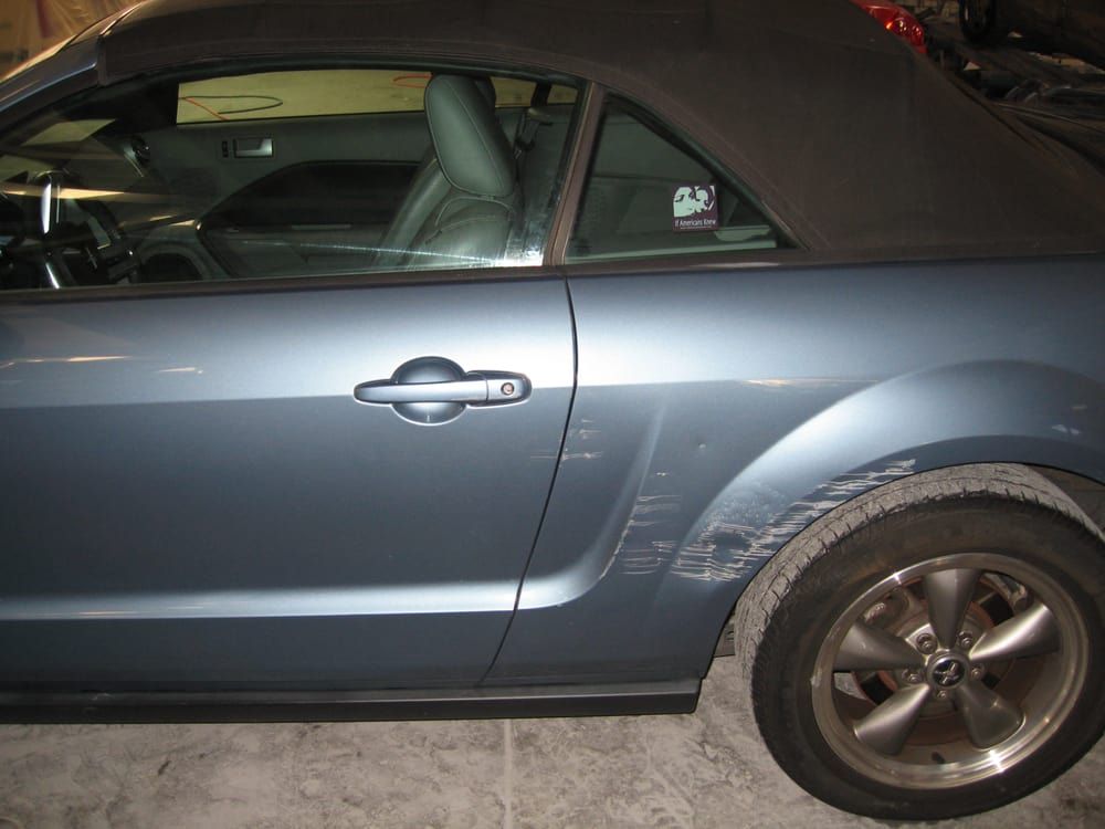 A blue convertible mustang is parked in a garage