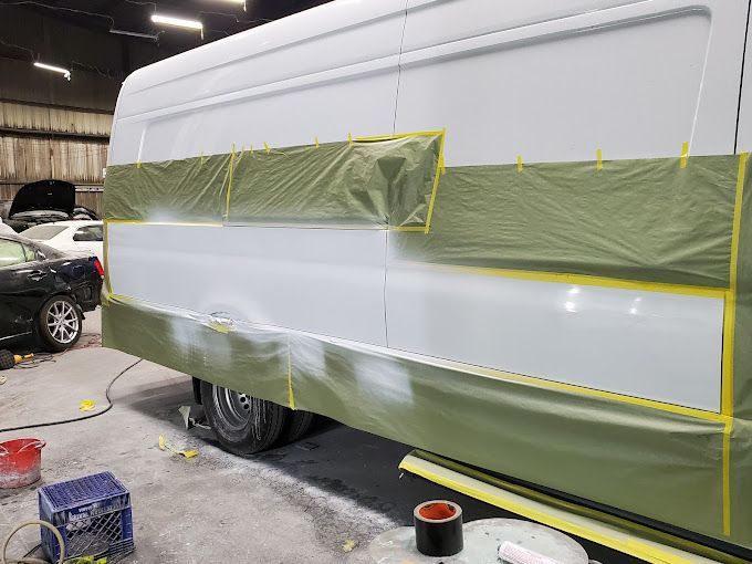 A white van is being painted in a garage.