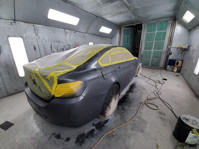 A car is being painted in a paint booth.
