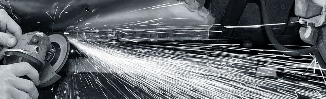 A black and white photo of a person spraying water on a metal surface.