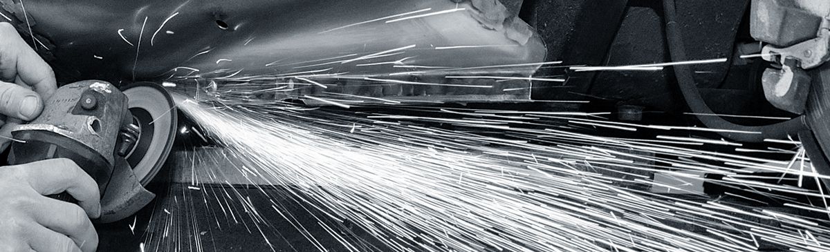 A black and white photo of a person spraying water on a metal surface.