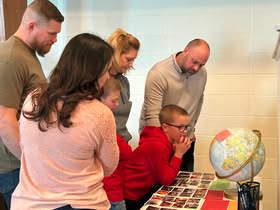 Small group gathered around a table studying a colorful globe in a classroom.