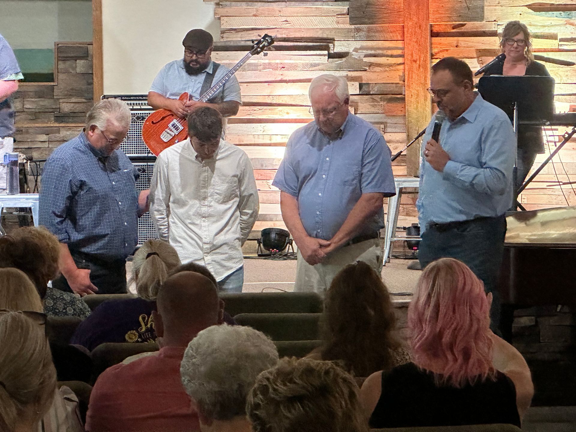 People on a stage bowing before an audience in a church or community hall