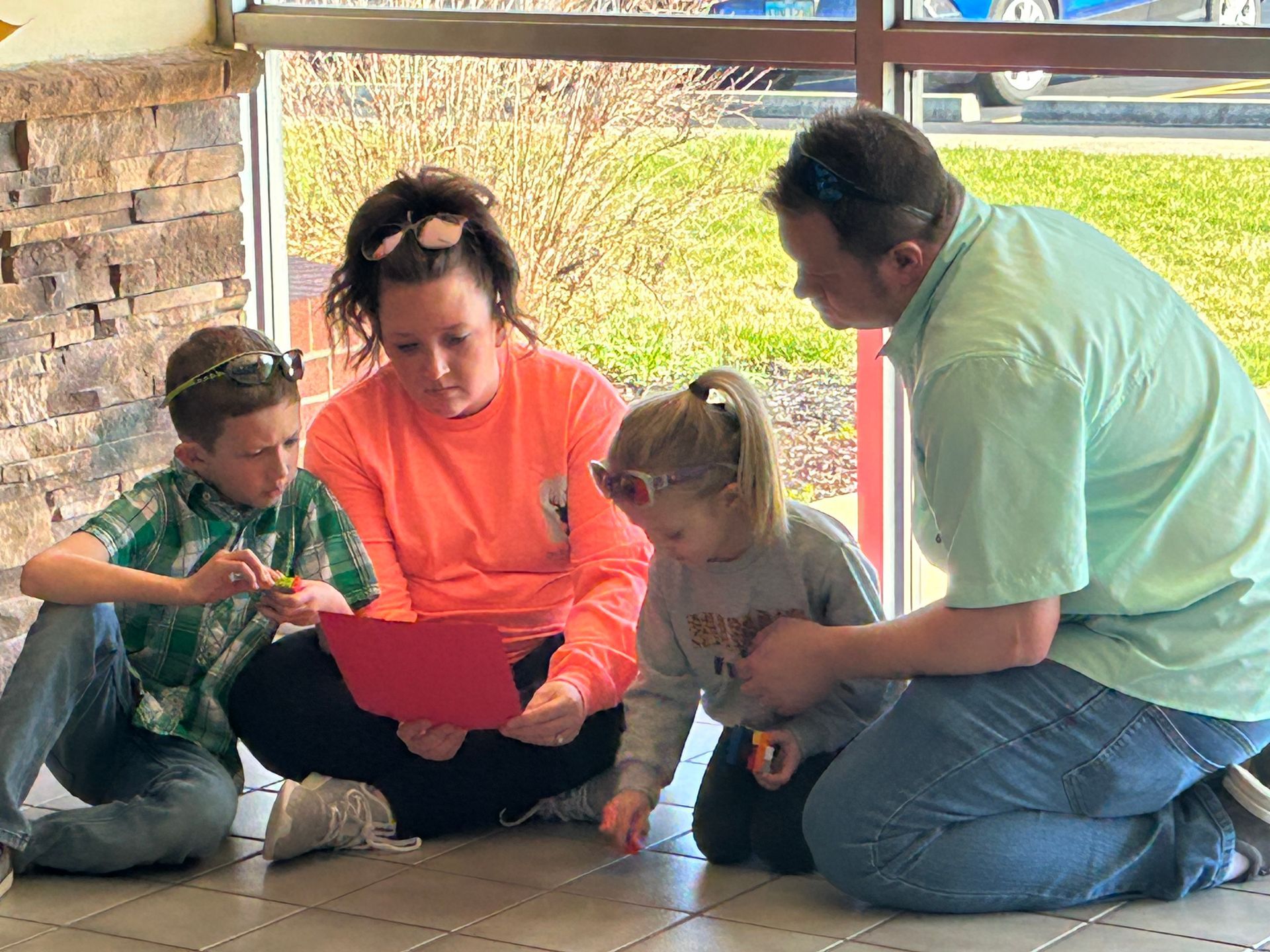 Family gathered on a porch, looking at a tablet together.