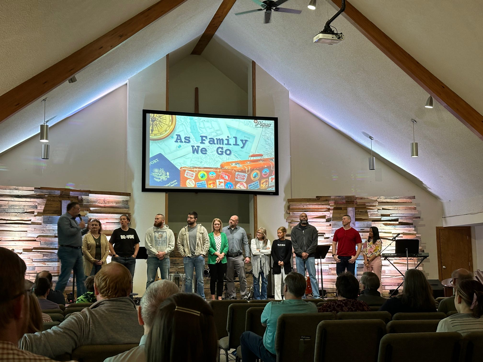 Church stage with a choir standing before a screen that says “As for me and my house, we will serve the Lord”