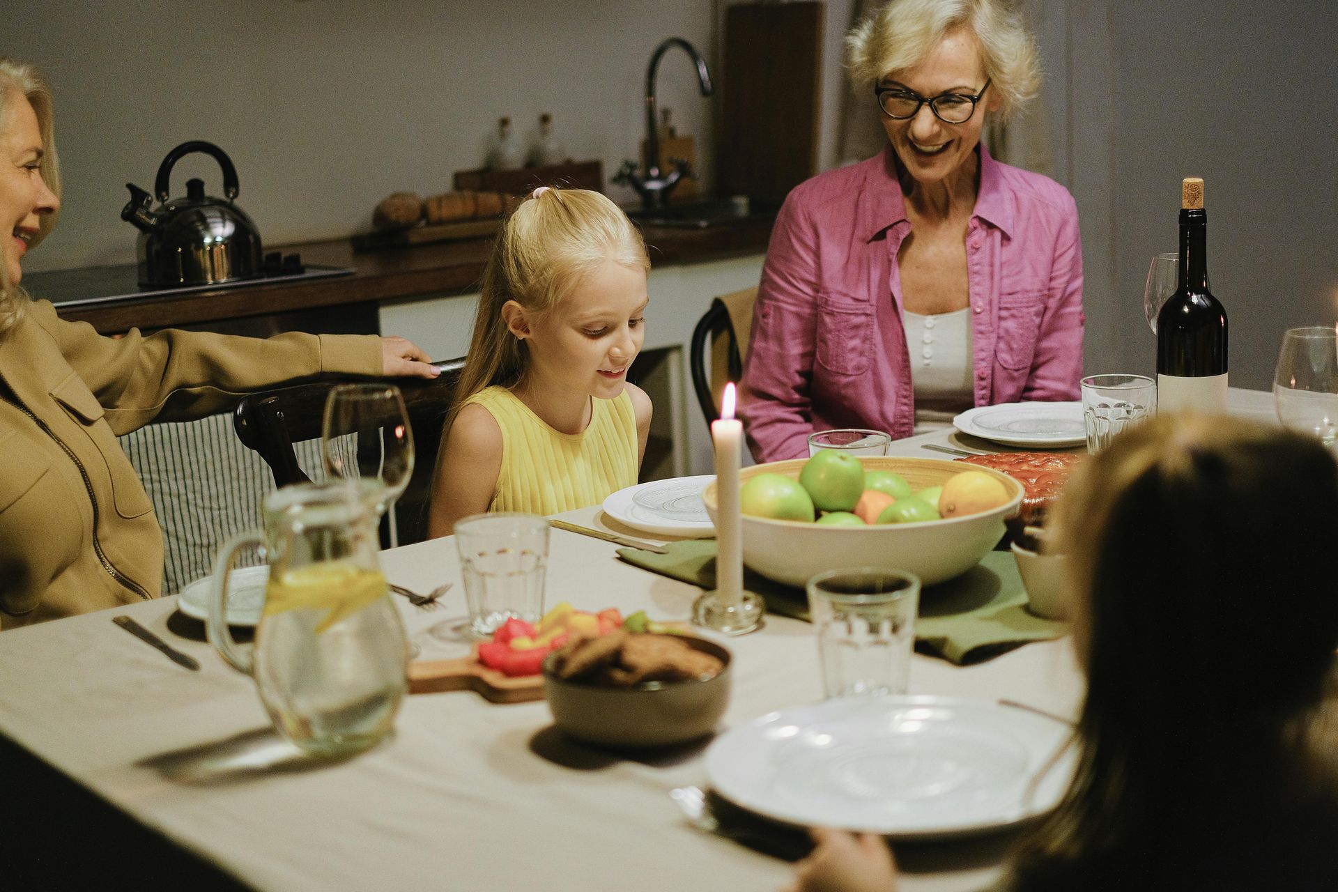 Family gathered around a dining table with a child, food, and drinks during a meal