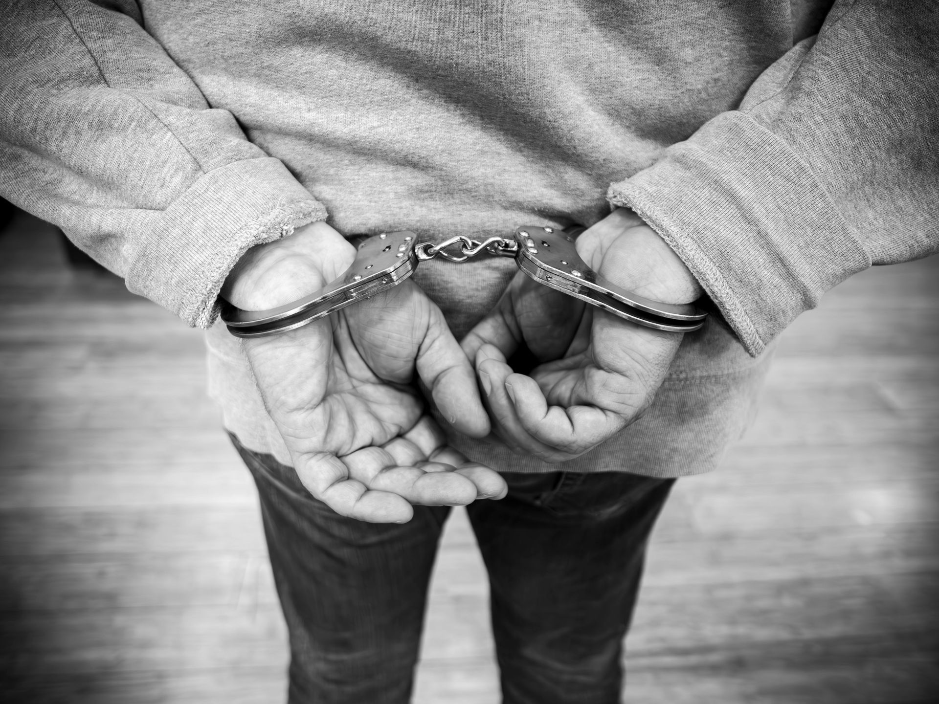 Man in handcuffs with hands bound behind back