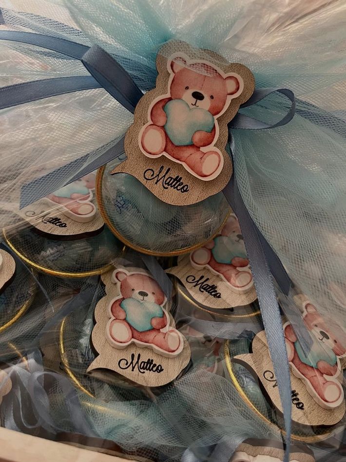 Bomboniere impilate per baby shower con nastri blu e targhette a forma di orsacchiotto con le scritte 