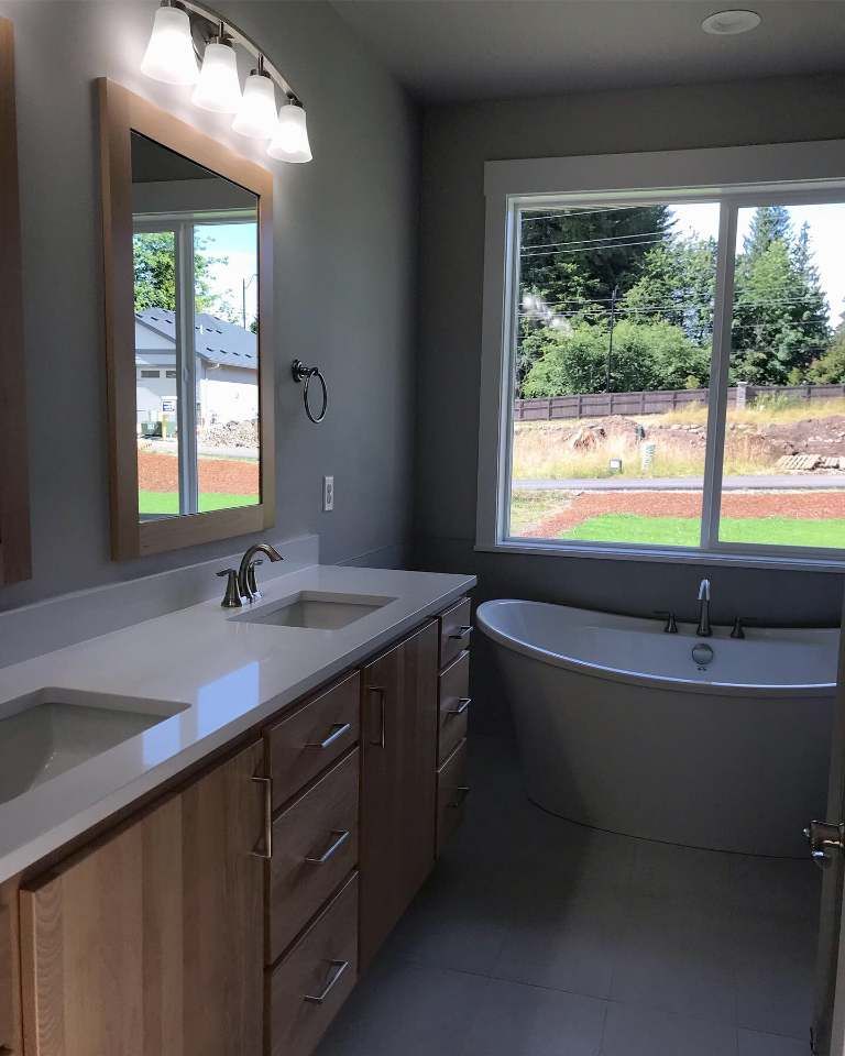 A bathroom with a tub , sink , mirror and window