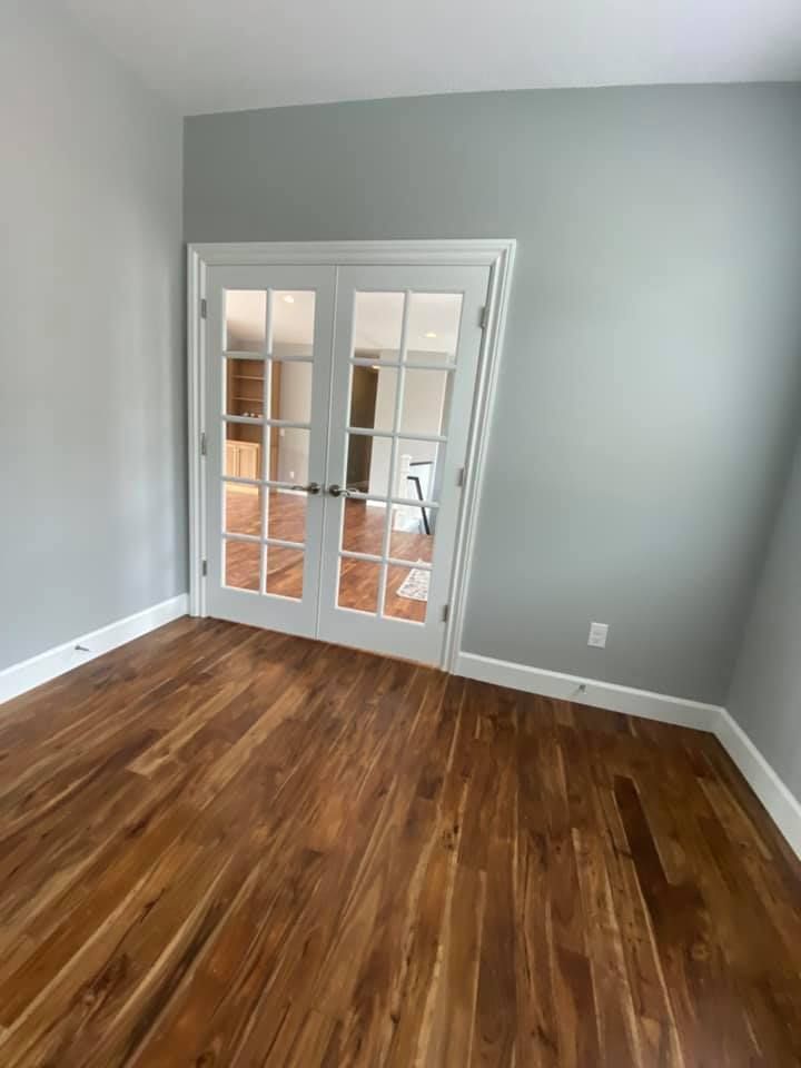 An empty room with hardwood floors and french doors.