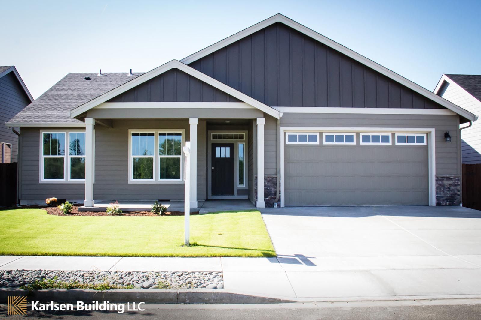 A gray house with a black roof and white trim