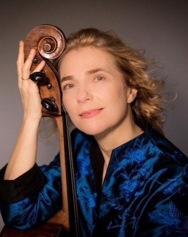 A woman in a blue jacket is holding a double bass.