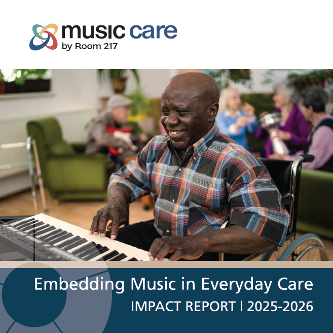A woman wearing a mask is playing a drum for an elderly woman in a wheelchair.