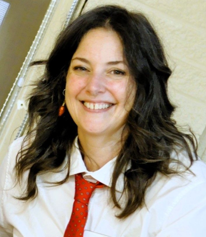 A woman wearing a white shirt and a red tie smiles