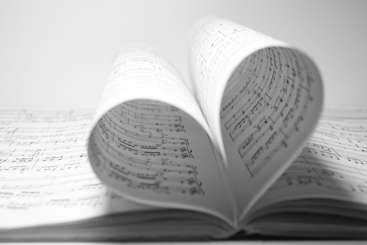 A heart shaped piece of music is sitting on top of an open book