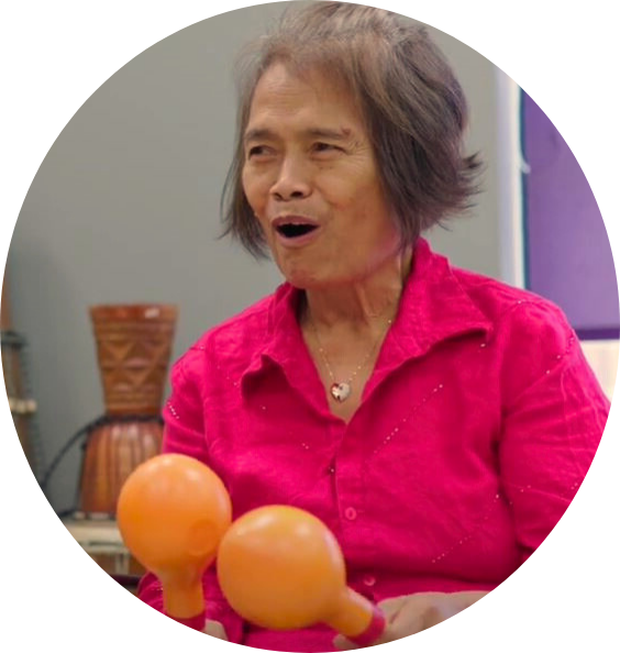 A woman in a pink shirt is holding two orange maracas