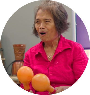 A woman in a pink shirt is holding two orange maracas
