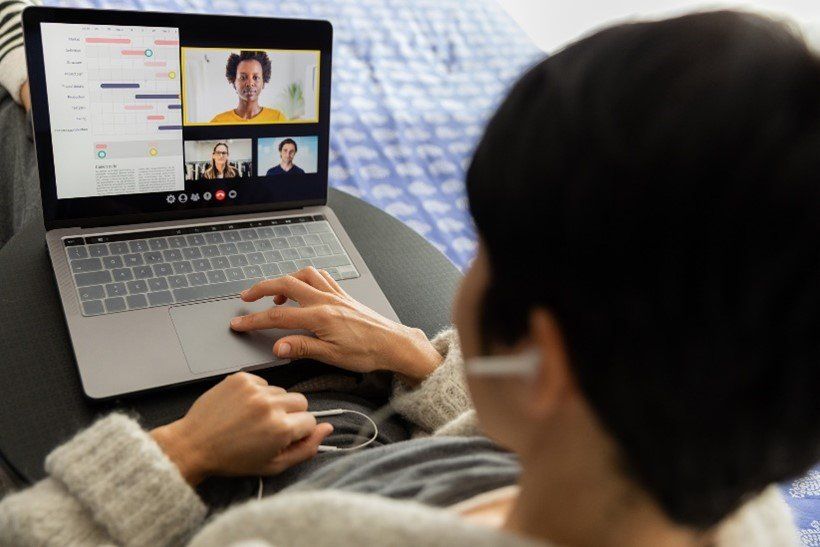 A woman is sitting on a couch using a laptop computer.