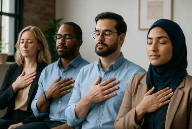 Four diverse people in business attire, eyes closed, hands on chests, meditating.