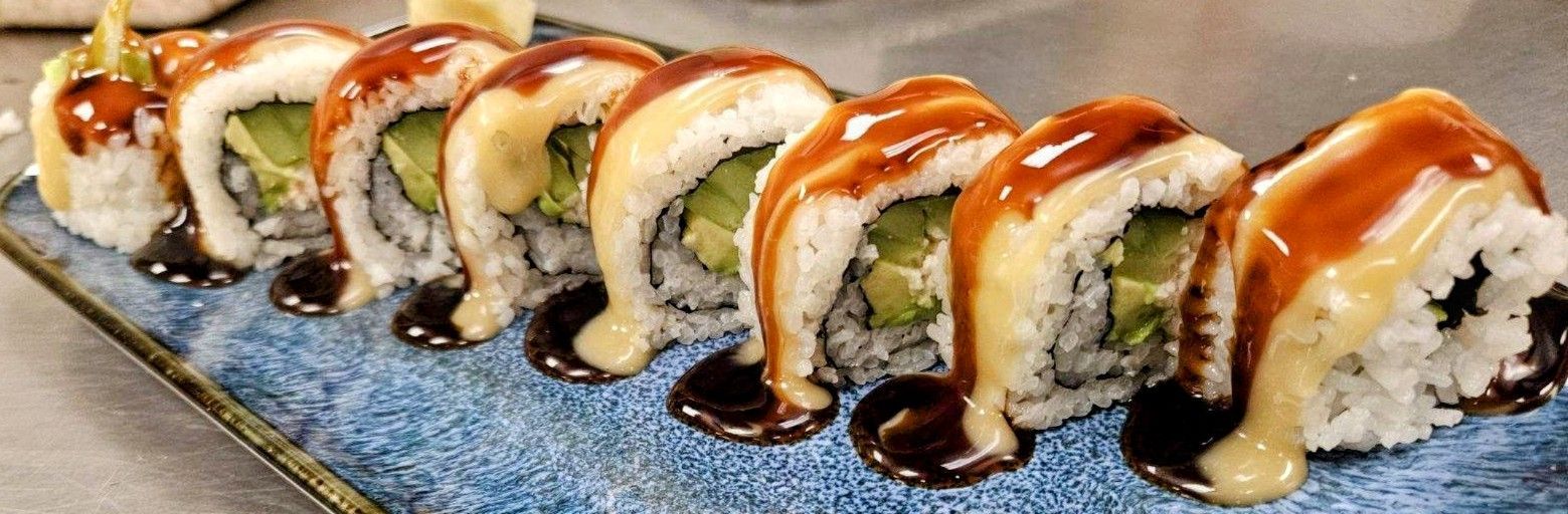 Sushi rolls drizzled with creamy and dark sauces on a blue plate