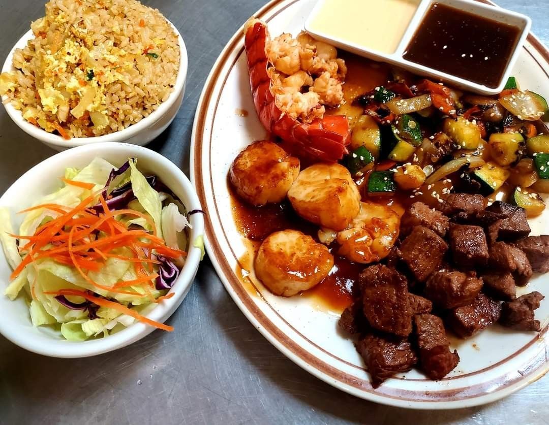 Plated Asian meal with fried rice, salad, shrimp, meat, vegetables, and dipping sauce
