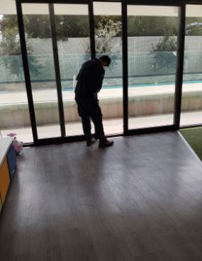 Persona inclinándose junto a unas grandes puertas de cristal en una habitación luminosa