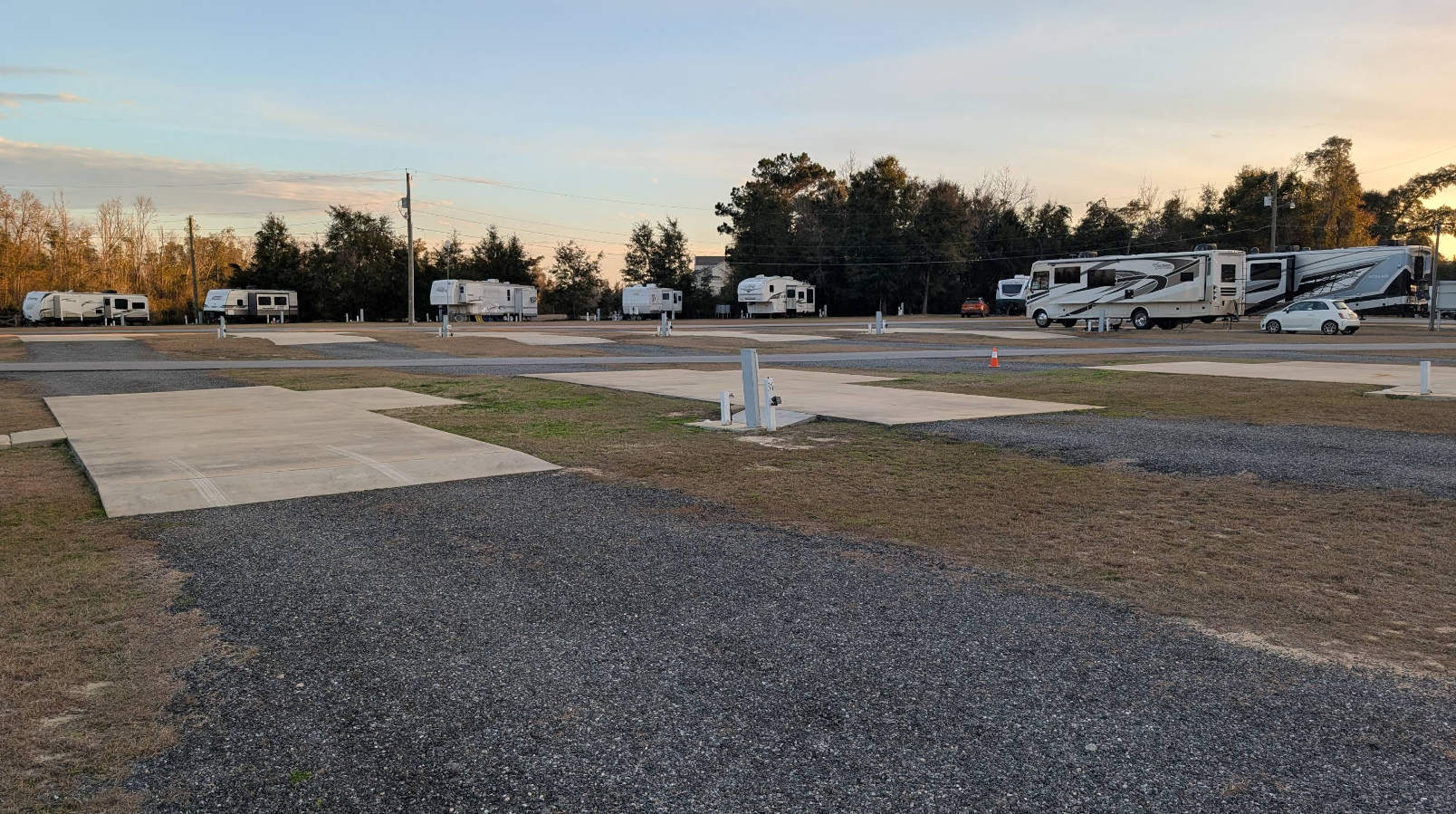 RV campsite with gravel and concrete pads; RVs parked.