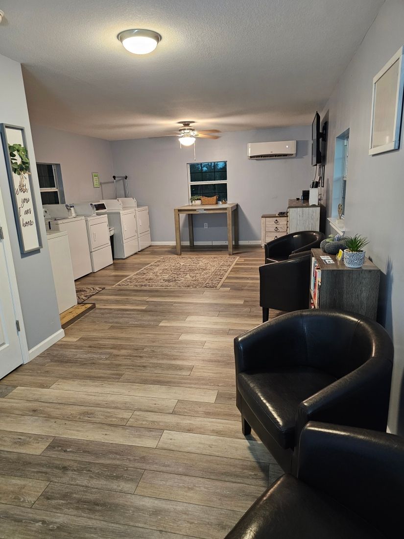 Interior of a laundromat with washers and dryers, seating, and a table.
