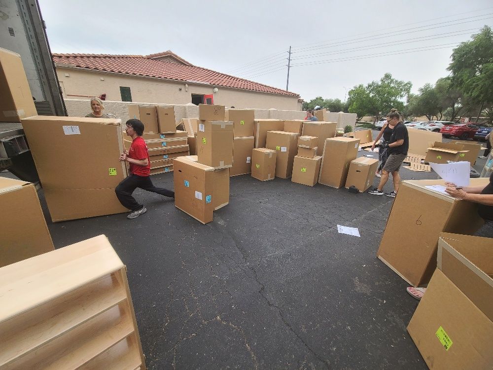 A group of people are moving boxes in a parking lot.