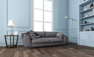 Cozy gray sofa in a light blue living room with window, lamp, and built-in shelves.