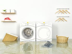 Flooded laundry room with washing machine, soaking floor, and floating laundry items