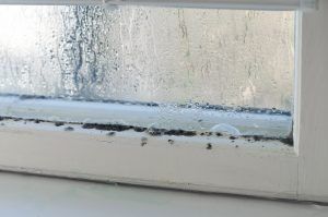 Fogged window with condensation and water droplets on the glass and sill