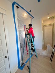 Worker in a white hard hat measures a wall with a level during interior renovation