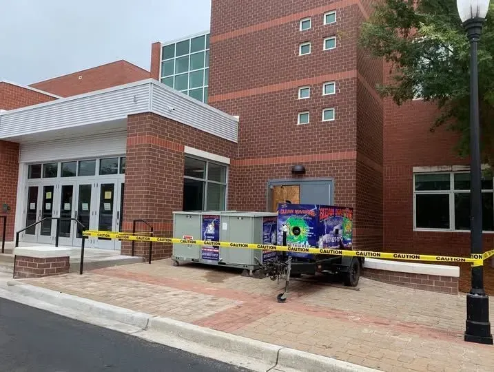 Caution-taped brick building entrance with a colorful utility trailer parked on the sidewalk