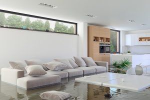 Modern living room with a light sofa, white coffee table, and large window; open kitchen in the background