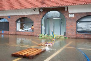 Flooded brick building entrance with standing water and debris on the pavement