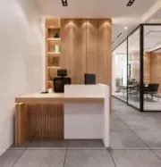 Modern office reception desk with wood accents, glass walls, and tiled floor in a minimalist lobby