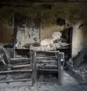 Burned-out room with charred chairs and walls, debris covering the floor