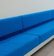 Long blue upholstered bench seating along a white wall in a modern interior