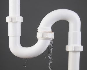 White PVC pipe joint leaking water against a gray background