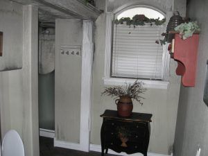 Small entryway with a white window, black cabinet, and potted plant beneath an arched doorway.