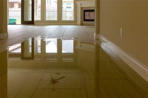 Flooded living room with water reflecting the windows and fireplace.