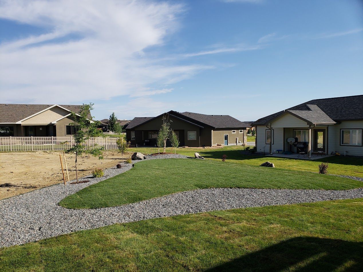 Suburban homes with a landscaped front yard, curved gravel path, and blue sky