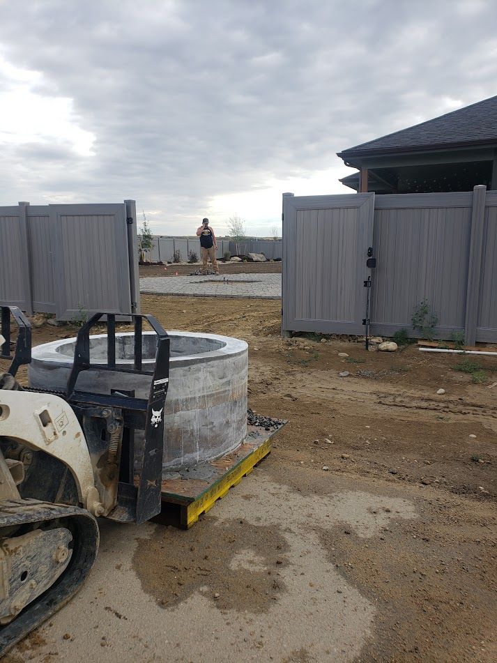 Construction site with a skid steer, concrete barriers, and a fenced area under cloudy skies