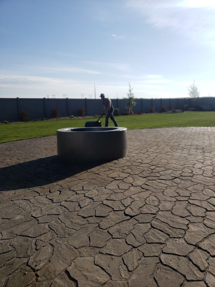 Person standing on a large concrete cylinder in a sunny park with cracked pavement.